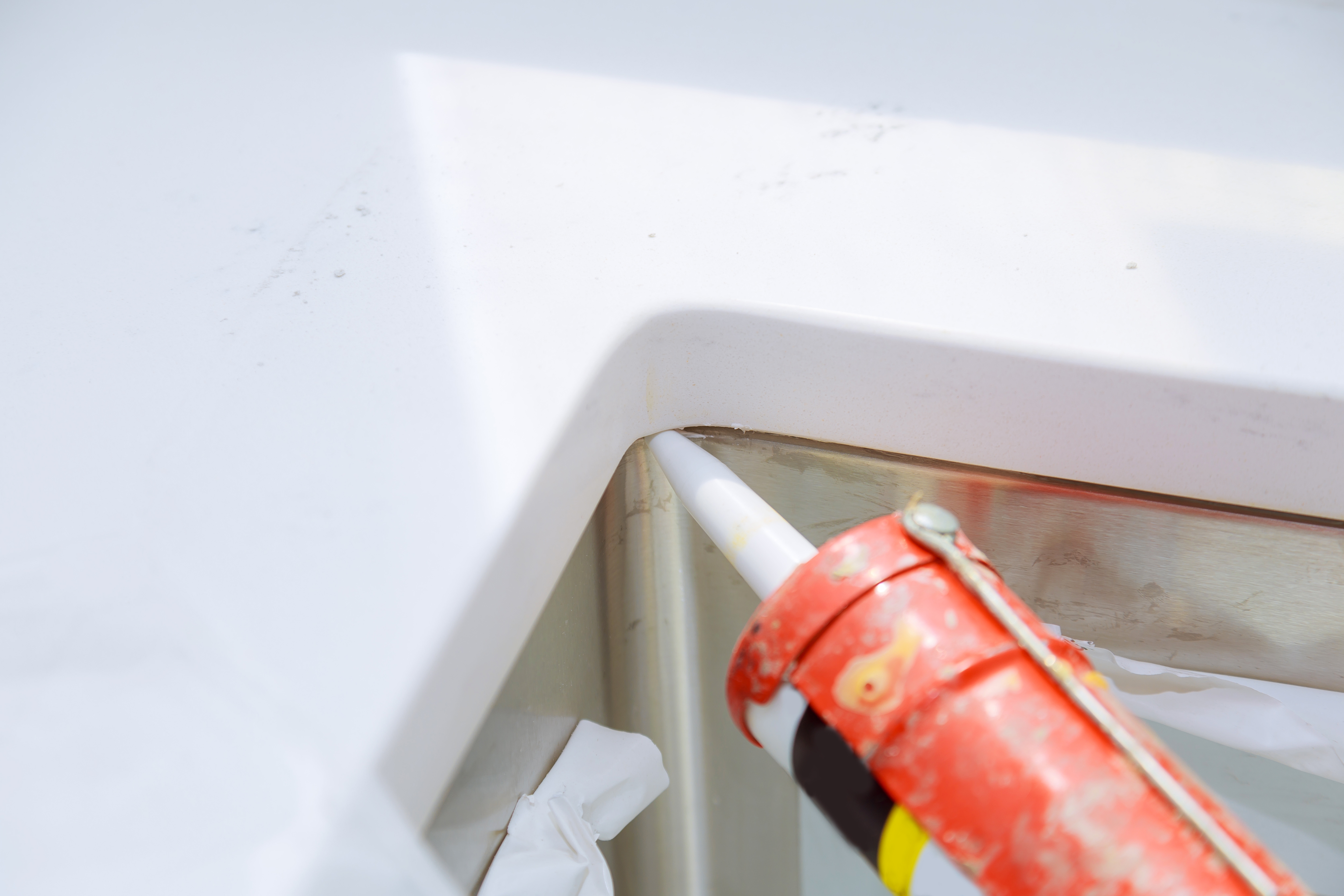 worker-installing-granite-sink-in-kitchen-silicone-2023-11-27-04-53-11-utc